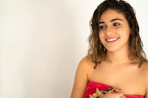 A closeup shot of an attractive young lady with a nose piercing covered with a towel after a bath