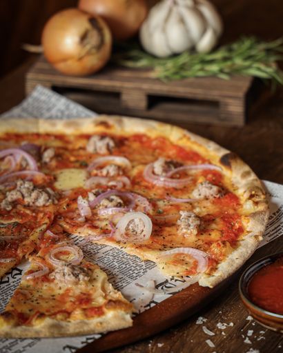 A vertical shot of pizza with onion and meat