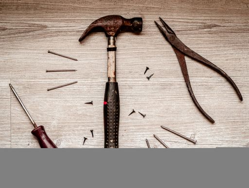 A high angle view of old rusty hand tools on a wooden table under the light