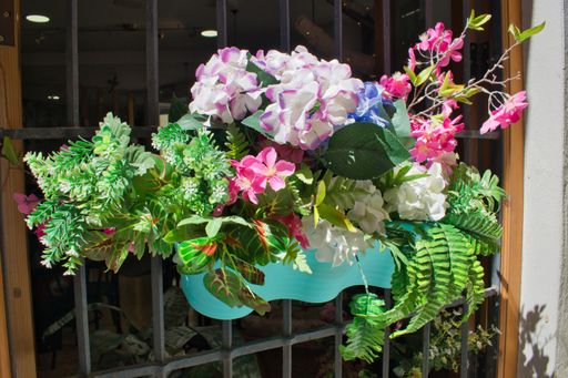 A closeup of a colorful flowerpot with artificial flowers on a street in Valencia, Spain