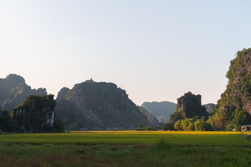 A beautiful shot of the limestone rocks behind rice terraces and fields in Ninh Binh, Northern Vietnam, during sunset