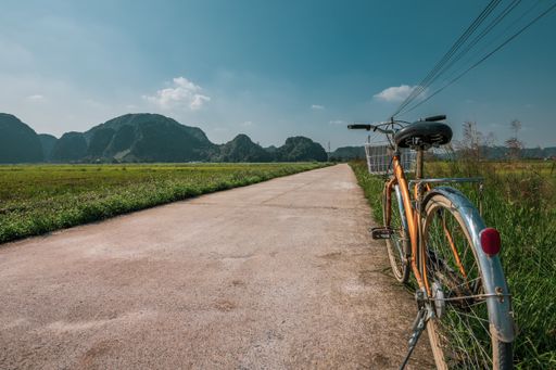 A bicycle parked on the side of a road between rice terraces in Ninh Binh, Northern Vietnam during sunset