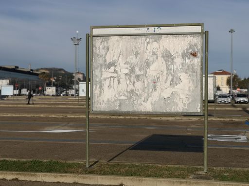 An old blank advertising sign with torn posters on an urban street