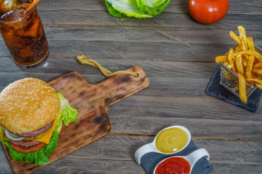 hamburger complete with two meats, sauces, french fries and cola on an antique wooden board.and copy space