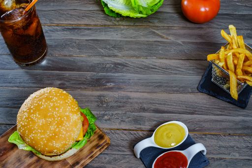 hamburger complete with two meats, sauces, french fries and cola on an antique wooden board.and copy space
