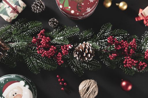 A top view shot of pine branches with cone and gift on a black background - concept of Christmas