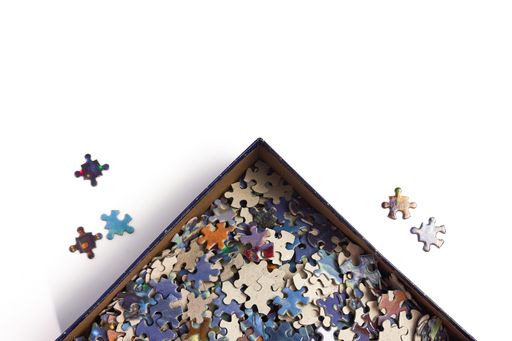 A top view of puzzle pieces in a box on a white surface with space for text