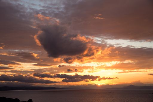 A landscape of the Aegean Sea under a cloudy sky during a beautiful golden sunset in Skiathos, Greece