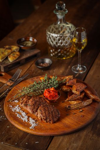 A vertical shot of fried potatoes with meat and sauce on a wooden board on the table