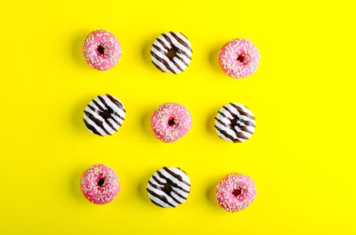 A high angle shot of three raws of donuts on a yellow background - perfect for a cool wallpaper