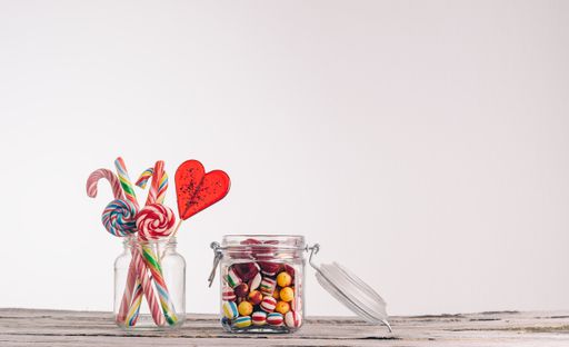 A closeup shot of candy canes and other candies in glass jars on a wooden surface - perfect for a cool wallpaper