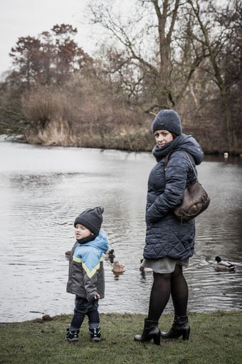 Woman and child standing in front of a pond in the winter season.