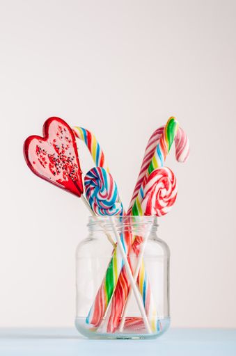 A vertical closeup shot of candy canes and other candies in glass jars - perfect for a cool wallpaper