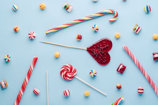 A high angle shot of candy canes and lollipops on a light blue background - perfect for a cool wallpaper