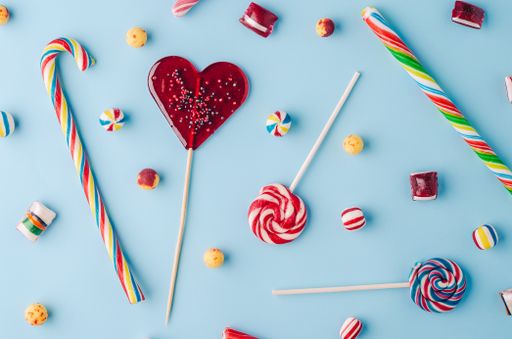 A high angle shot of candy canes and lollipops on a light blue background - perfect for a cool wallpaper