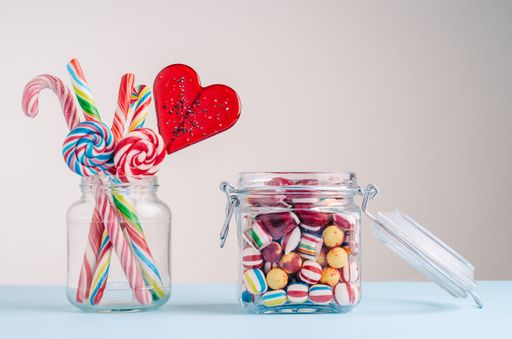 A closeup shot of candy canes and other candies in glass jars - perfect for a cool wallpaper