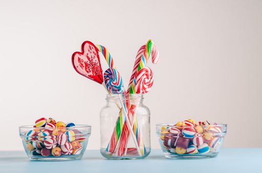 A closeup shot of candy canes and other candies in glass jars - perfect for a cool wallpaper