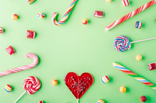 A high angle shot of candy canes and lollipops on a green background - perfect for a cool wallpaper