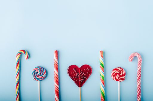 A high angle shot of candy canes and lollipops on a light blue background - perfect for a cool wallpaper