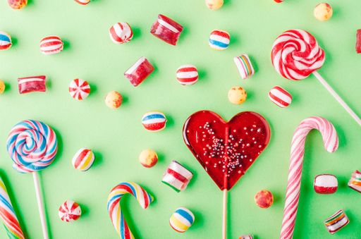 A closeup shot of candy canes and other candies on a green background - perfcet for a cool wallpaper