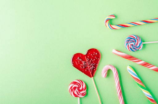 A closeup shot of candy canes and lollipops on a green background - perfcet for a cool wallpaper