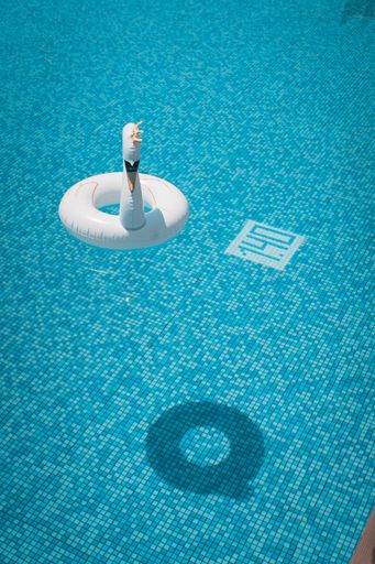 An Inflatable swan with a crown floating on the pool in the summer