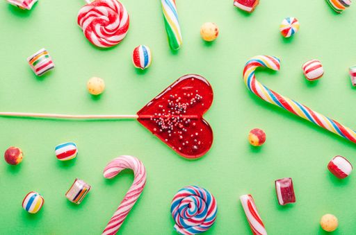 A closeup shot of candy canes and other candies on a green background - perfcet for a cool wallpaper