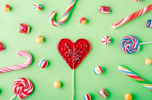 A closeup shot of candy canes and other candies on a green background - perfcet for a cool wallpaper