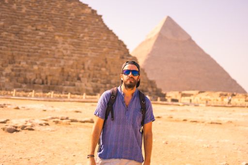 A male Caucasian photographer posing in front of the great pyramids of Giza in Egypt