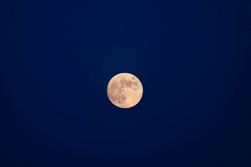 A beautiful closeup of a full moon on a blue sky background