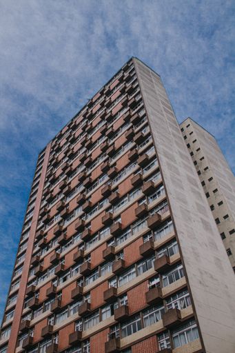 A vertical shot of a big urban building with balconies and a lot of windows in the daytime