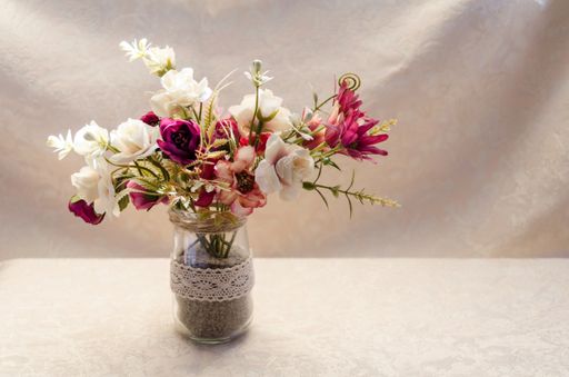 A closeup shot of colorful decorative flowers in a vase isolated on the beige background