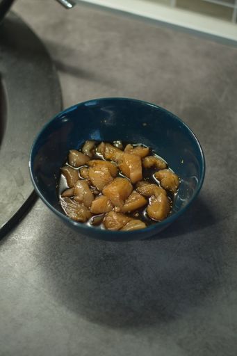 A vertical shot of uncooked chicken breasts soaked in the sauce before put in the frying pan
