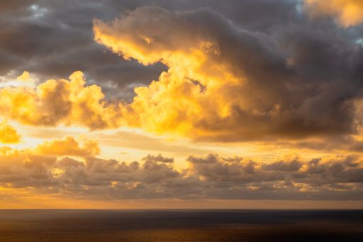 Aerial view of evening sun hiding behind group of dark clouds