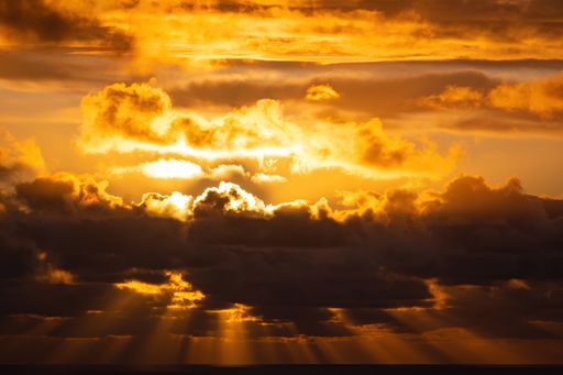 Aerial view of evening sun hiding behind group of dark clouds