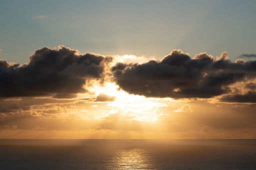 View of dark clouds lit by bright sunset light with fading blue sky above