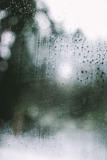 Condensation and fresh raindrops against the window of a car