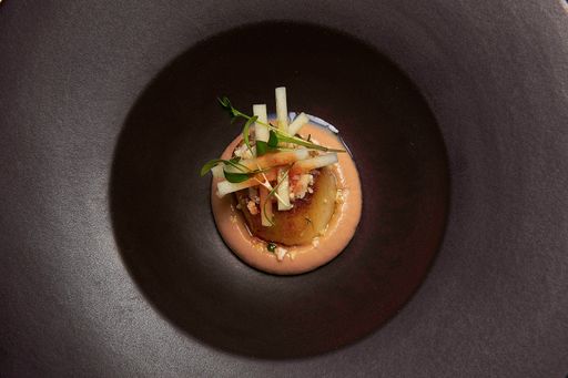 A top view of delicious cooked fish garnished with greens and vegetables on a black plate