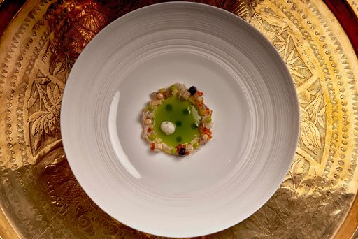 A top view of a delicious fish garnished with peas and aloe in a puree on a plate on a wooden table
