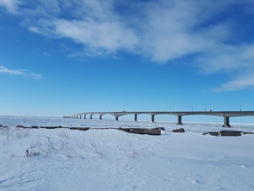 A beautiful shot of a concrete bridge on a snowy field under a cloudy sky