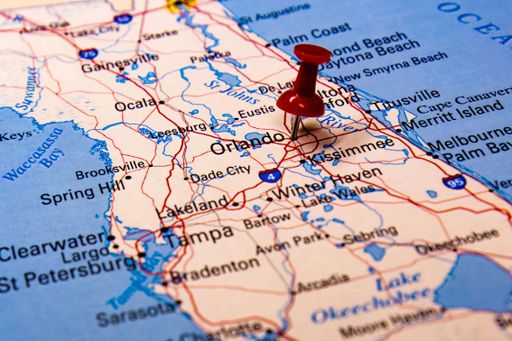 A closeup shot of a traveling red push pin on a map on the city of Orlando