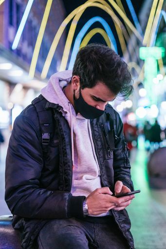 A shot of a man in a medical mask  looking at his phone