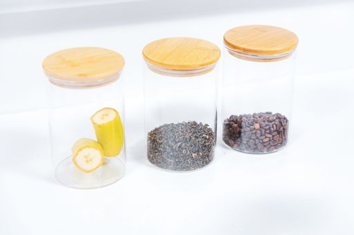 A closeup shot of three jars with bananas and two other spices on a white table