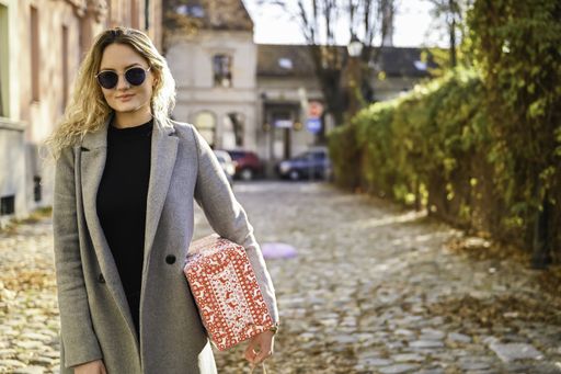 A selective focus shot of a stylish girl on the street with a box in her hand