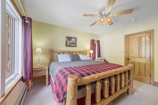 An interior shot of a bedroom with a ceiling fan, a log bed and light yellow walls.