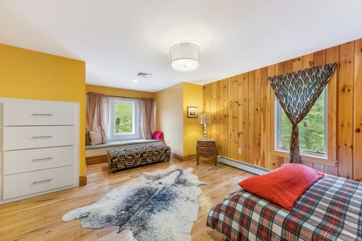 An interior shot of a wooden bedroom with a white ceiling and a decorative carpet.