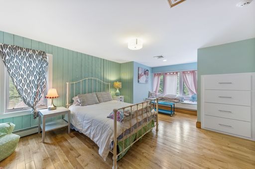 An interior shot of a bedroom with green walls and a wooden floor.