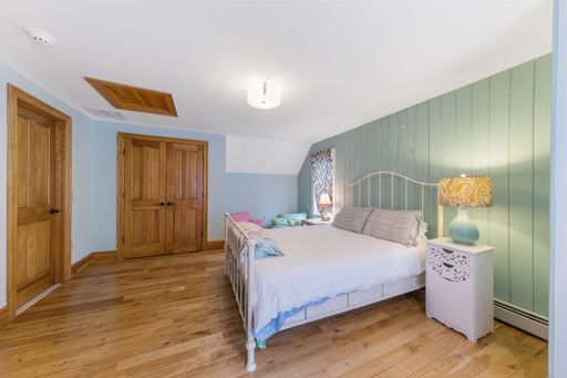 An interior shot of a bedroom with green walls and wooden floor and doors.