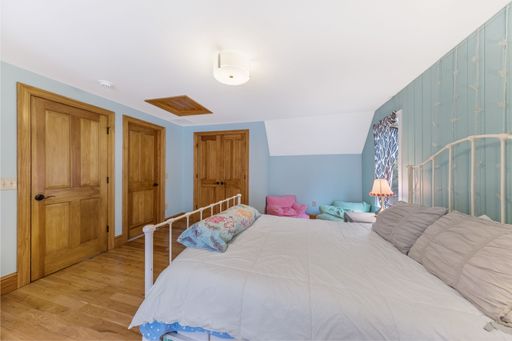 An interior shot of a bedroom with green walls and wooden floor and doors.
