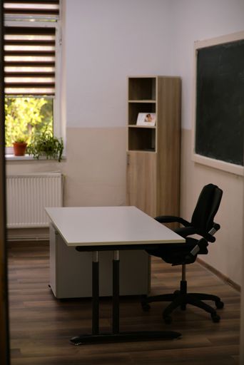 A vertical shot of a modern classroom with table and chair on background of a blackboard